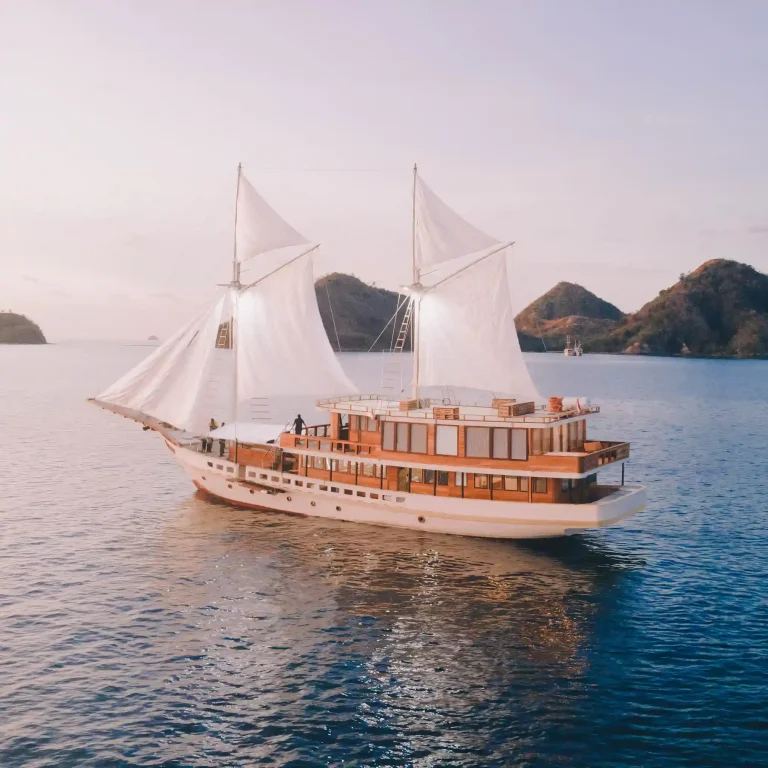 The phinisi Elbark with sails raised off a Komodo island